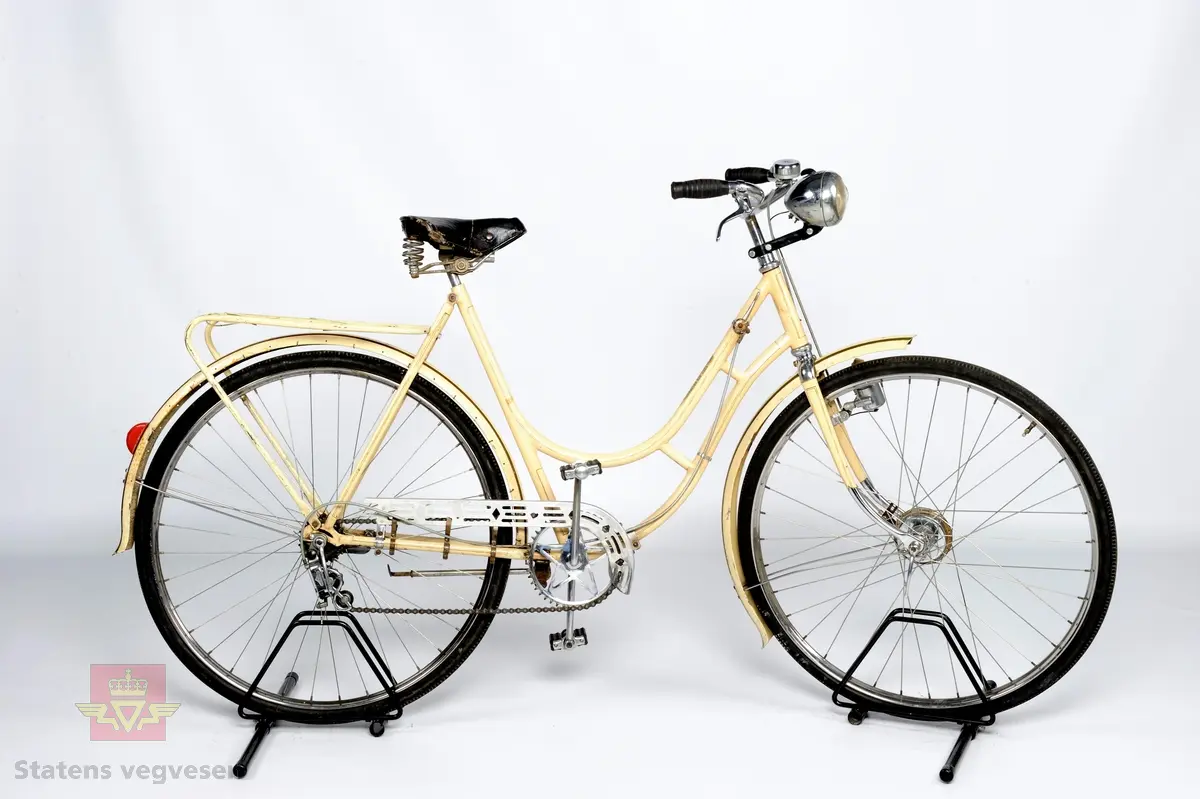 Damesykkel. Størrelse: 22" = 56 cm. Dekk: 28 x 1 1/2 = 40 - 635 mm. Nav foran: JØS 90 mm trommelbremsenav. Bak: Sachs Torpedo frinav med pedalbrems og 3 utvendige kjedegir. Hovedfarge er lys hvit. Trolig omlakkert.