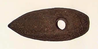 Skafthålsyxa av grovkornig gråbrun bergart. Ett stort och kraftigt exemplar. Plan undersida. Välvda smalsidor, vilka utan begränsningslinjer övergår i ovansidan. Delvis slipad.