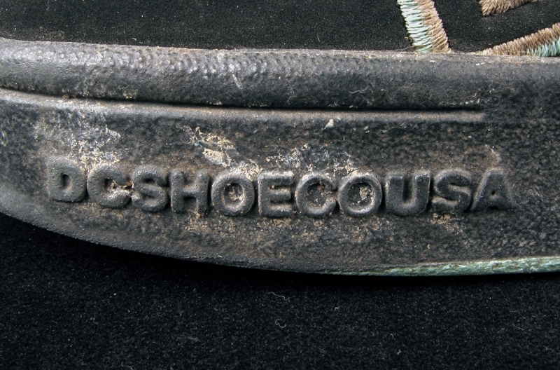 a) skateboardbräda av trä. Hjul saknas. Mått: längd 77,5 cm, bredd 19 cm, tjocklek 1 cm.
b1-b2) svarta skateskor. Märke: DC Shoe.
Märkning: "DCSHOECOUSA".
 Mått: längd 23 cm, bredd 9 cm, höjd 8,5 cm.
c1-c2) vita skateskor.  Märke: DC Shoe. 
Märkning: "DCSHOECOUSA". 
Mått: längd 22 cm, bredd 8, 5 cm, höjd 8,5 cm.