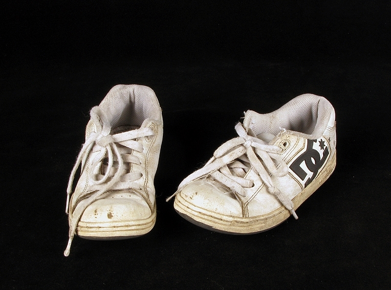 a) skateboardbräda av trä. Hjul saknas. Mått: längd 77,5 cm, bredd 19 cm, tjocklek 1 cm.
b1-b2) svarta skateskor. Märke: DC Shoe.
Märkning: "DCSHOECOUSA".
 Mått: längd 23 cm, bredd 9 cm, höjd 8,5 cm.
c1-c2) vita skateskor.  Märke: DC Shoe. 
Märkning: "DCSHOECOUSA". 
Mått: längd 22 cm, bredd 8, 5 cm, höjd 8,5 cm.