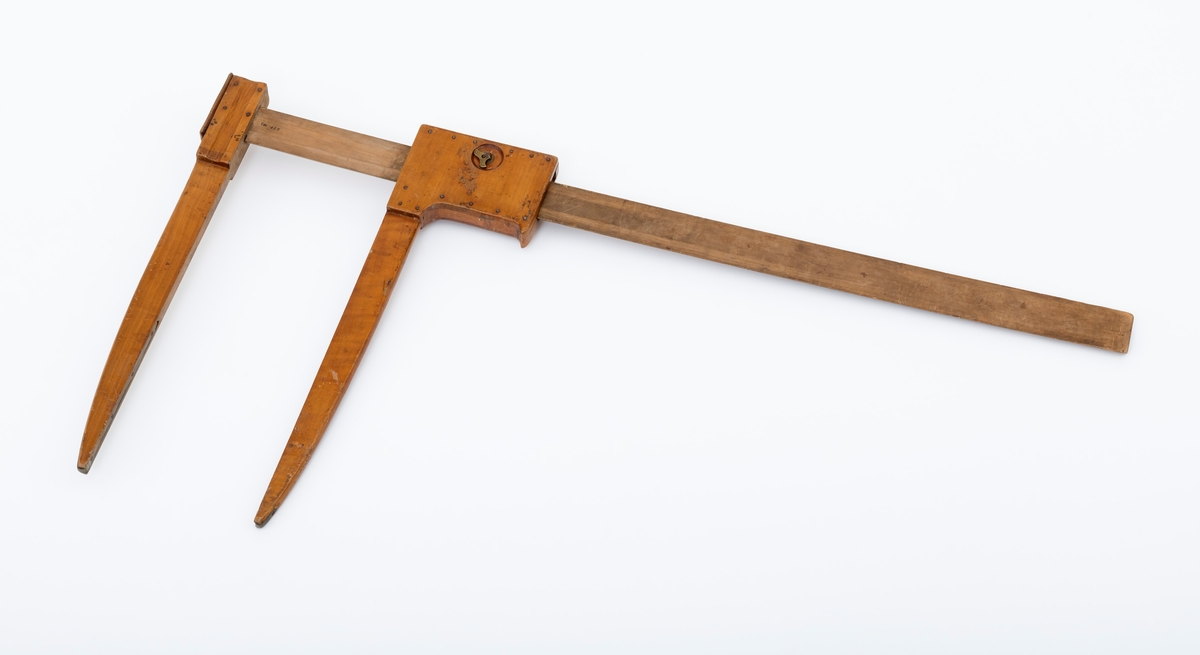 Uvanlig stor måleklave, såkalt «skyveklave», for diameterundersøkelser av stående trær og tømmerstokker. Klaven er lagd av tre. Den har en 101,9 centimeter lang linjal (inkludert den delen som er tappet gjennom den faste klavearmen). Klavelinjalen er 5,0 centimeter bred og snaut 1,4 centimeter tjukk. I den ytre enden er det påtappet en fast klavearm som er 50,6 centimeter lang, hvorav 43,0 centimeter er på den sida av linjalen som skulle vendes mot det objektet som skulle måles. Klaven har også en bevegelig arm, dimensjonert og formet som den faste, men innfestet et 15,7 centimeter langt og 9,5 centimeter bredt (midtmål) handtak, som brukes til å manøvrere den bevegelige armen langs klavelinjalen. Handtaket har en messingskrue, som antakelig skulle kunne regulere friksjonen mellom den bevegelige klavearmen og linjalen. Treverket i linjalen har en påtrykt måleskala med strekmarkeringer med centimetermål på den ene flatsida. Målene avleses der innerkanten av den bevegelige armen møter linjalen når klavearmene ligger an mot barken eller yteveden på trær eller tømmerstokker som skal diametermåles.

Dette er en tyskprodusert tømmerklave, lagd for diametermålinger i et skogbruk der det kunne forekomme trestammer med diametermål som var langt større enn dem som var vanlige i norsk skogbruk. Klavertypen skal særlig ha vært brukt under taksasjonsarbeid.

Eldre gjenstandsbeskrivelse:
«Klaven er lakkert lys brun. Armene er 4 cm brede og 1, 7cm tykke. Mot spissene er de messingbeslått. Den beveglige armen har et kraftig håndtak, 15, 8cm langt og 9, 5cm bredt. Den kan låses med en messingskrue. Denne klaven er en s. k. Heyer-Standinger-klave s om ble brukt mye til taksasjon.»