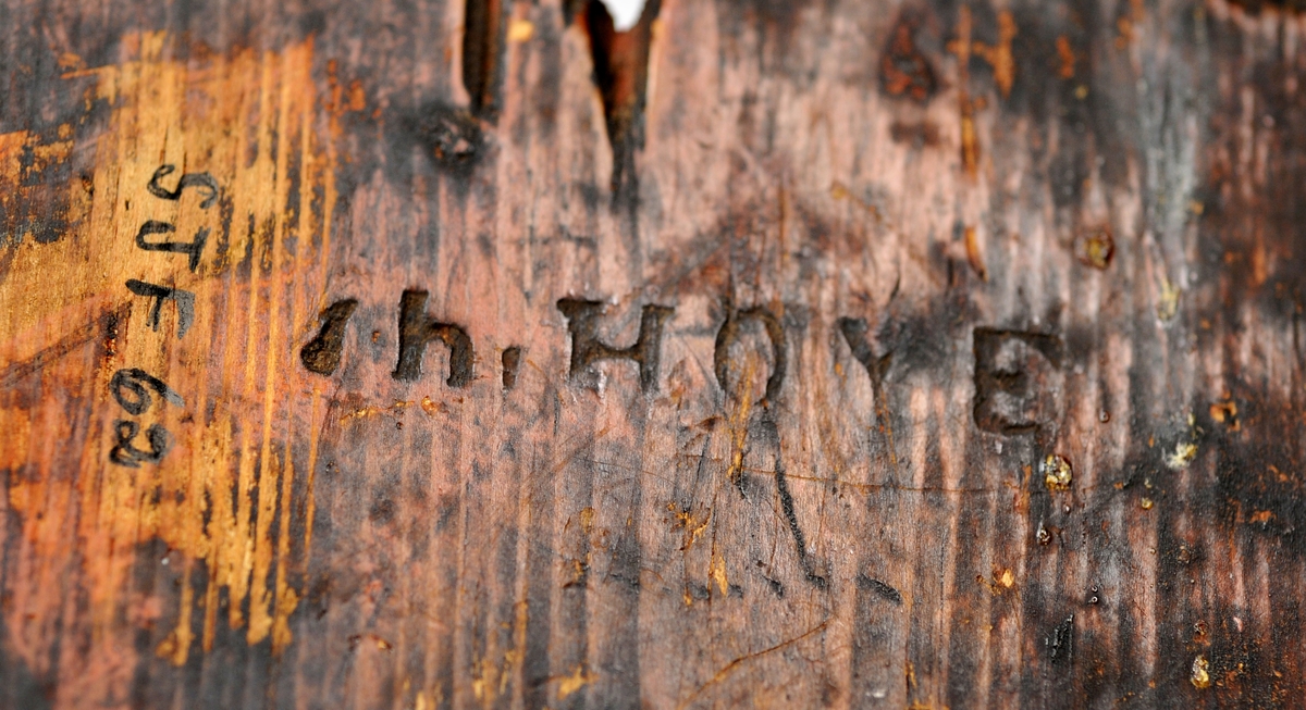 Sveipet laup med rett bakstykke, lagd for å kunne henges på en vegg, der den skulle henge som en beholder, opprinnelig sannsynligvis på et kjøkken. Sett rett ovenfra eller nedenfra er laupen formet som en halvoval. De veggene som skulle vende fram i rommet er lagd av tre forholdsvis tynne (7-8 millimeter) bjørkeskier, som er bøyd i en U-form. Endestykkene er festet i slisser langs kantene av bakstykket ved hjelp av trenagler. Disse tre komponentene er bundet sammen, kant mot kant ved hjelp av bindsler av trefibermateriale. Ytterflatene har svidekor - bølgemønstere på den øverste og nederste, og en akantusranke på den midtre, som er noe bredere enn de to andre. Bakstykket - ryggfjøla - er lagd av et 21,3 centimeter bredt og 1,9 centimeter tjukt (3/4-toms) bord, antakelig av granvirke. Det er vinkelrett avkuttet i den nedre enden, men overenden er avrundet og profilert. Her er det fire gjennbombrutte hull, hvorav tre er runde og det fjerde er firefliket. Det øverste av disse har vært brukt ved oppheng. Også denne delen av laupen har svidekor med elementer av de samme formene som finnes på veggenes forsider. På baksida er det innsvidd en ring, sammensatt av små sirkler, som omgir initialer og årstall: «KSS 1817». Forsida er svijernstemplet «Jh. HØYE». Laupen har et halvovalformet lokk, lagd av granvirke og prydet med et innsvidd mønster, bestående av sirkler, halvsirkler og akantusblader. Også her finner vi det nevnte svijernstempelet. Lokket og bakstykket kan se ut til å ha vært innsatt med et rødbrunt fargestoff. Opprinnelig hengsling mangler. Botnstykket mangler fullstendig, men et innfelt spor nederst på bakstykket og naglehull langs ytterkanten på den nederste buete skia antyder hvordan botnstykket har vært festet.