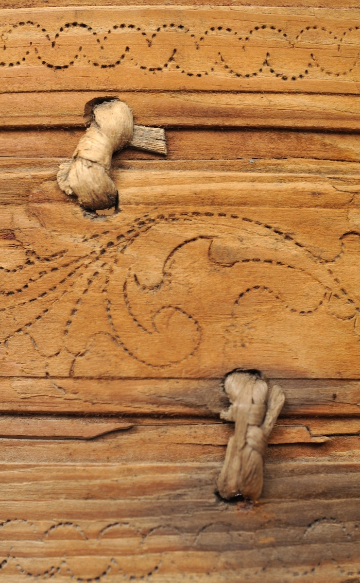 Sveipet laup med rett bakstykke, lagd for å kunne henges på en vegg, der den skulle henge som en beholder, opprinnelig sannsynligvis på et kjøkken. Sett rett ovenfra eller nedenfra er laupen formet som en halvoval. De veggene som skulle vende fram i rommet er lagd av tre forholdsvis tynne (7-8 millimeter) bjørkeskier, som er bøyd i en U-form. Endestykkene er festet i slisser langs kantene av bakstykket ved hjelp av trenagler. Disse tre komponentene er bundet sammen, kant mot kant ved hjelp av bindsler av trefibermateriale. Ytterflatene har svidekor - bølgemønstere på den øverste og nederste, og en akantusranke på den midtre, som er noe bredere enn de to andre. Bakstykket - ryggfjøla - er lagd av et 21,3 centimeter bredt og 1,9 centimeter tjukt (3/4-toms) bord, antakelig av granvirke. Det er vinkelrett avkuttet i den nedre enden, men overenden er avrundet og profilert. Her er det fire gjennbombrutte hull, hvorav tre er runde og det fjerde er firefliket. Det øverste av disse har vært brukt ved oppheng. Også denne delen av laupen har svidekor med elementer av de samme formene som finnes på veggenes forsider. På baksida er det innsvidd en ring, sammensatt av små sirkler, som omgir initialer og årstall: «KSS 1817». Forsida er svijernstemplet «Jh. HØYE». Laupen har et halvovalformet lokk, lagd av granvirke og prydet med et innsvidd mønster, bestående av sirkler, halvsirkler og akantusblader. Også her finner vi det nevnte svijernstempelet. Lokket og bakstykket kan se ut til å ha vært innsatt med et rødbrunt fargestoff. Opprinnelig hengsling mangler. Botnstykket mangler fullstendig, men et innfelt spor nederst på bakstykket og naglehull langs ytterkanten på den nederste buete skia antyder hvordan botnstykket har vært festet.