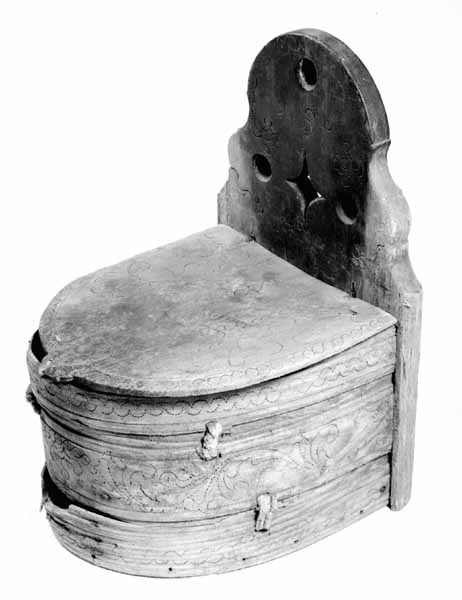 Sveipet laup med rett bakstykke, lagd for å kunne henges på en vegg, der den skulle henge som en beholder, opprinnelig sannsynligvis på et kjøkken. Sett rett ovenfra eller nedenfra er laupen formet som en halvoval. De veggene som skulle vende fram i rommet er lagd av tre forholdsvis tynne (7-8 millimeter) bjørkeskier, som er bøyd i en U-form. Endestykkene er festet i slisser langs kantene av bakstykket ved hjelp av trenagler. Disse tre komponentene er bundet sammen, kant mot kant ved hjelp av bindsler av trefibermateriale. Ytterflatene har svidekor - bølgemønstere på den øverste og nederste, og en akantusranke på den midtre, som er noe bredere enn de to andre. Bakstykket - ryggfjøla - er lagd av et 21,3 centimeter bredt og 1,9 centimeter tjukt (3/4-toms) bord, antakelig av granvirke. Det er vinkelrett avkuttet i den nedre enden, men overenden er avrundet og profilert. Her er det fire gjennbombrutte hull, hvorav tre er runde og det fjerde er firefliket. Det øverste av disse har vært brukt ved oppheng. Også denne delen av laupen har svidekor med elementer av de samme formene som finnes på veggenes forsider. På baksida er det innsvidd en ring, sammensatt av små sirkler, som omgir initialer og årstall: «KSS 1817». Forsida er svijernstemplet «Jh. HØYE». Laupen har et halvovalformet lokk, lagd av granvirke og prydet med et innsvidd mønster, bestående av sirkler, halvsirkler og akantusblader. Også her finner vi det nevnte svijernstempelet. Lokket og bakstykket kan se ut til å ha vært innsatt med et rødbrunt fargestoff. Opprinnelig hengsling mangler. Botnstykket mangler fullstendig, men et innfelt spor nederst på bakstykket og naglehull langs ytterkanten på den nederste buete skia antyder hvordan botnstykket har vært festet.