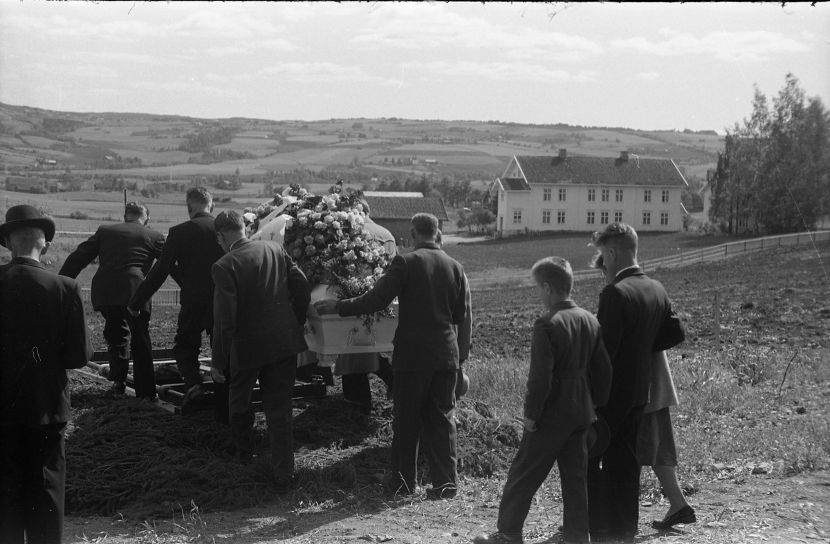 Begravelse ved Hoff kirke juni 1955. Serie på 9 bilder, der de første viser prosesjonen fra gravkapellet il grava, de øvrige ved grava. Ifølge informmant er dette begravelsen etter Ludvig Madshus som var kjøpmann i Lillo. Foraan prosesjonen går presten, som trolig er Finn Sommer, og kirketjener Pål Rødset. Nærmest bak kista trolig Ludvigs hustru Helga født Hagen, og deres to sønner Johan Ludvig (i midten) og Olav. De øvrige er ukjente.