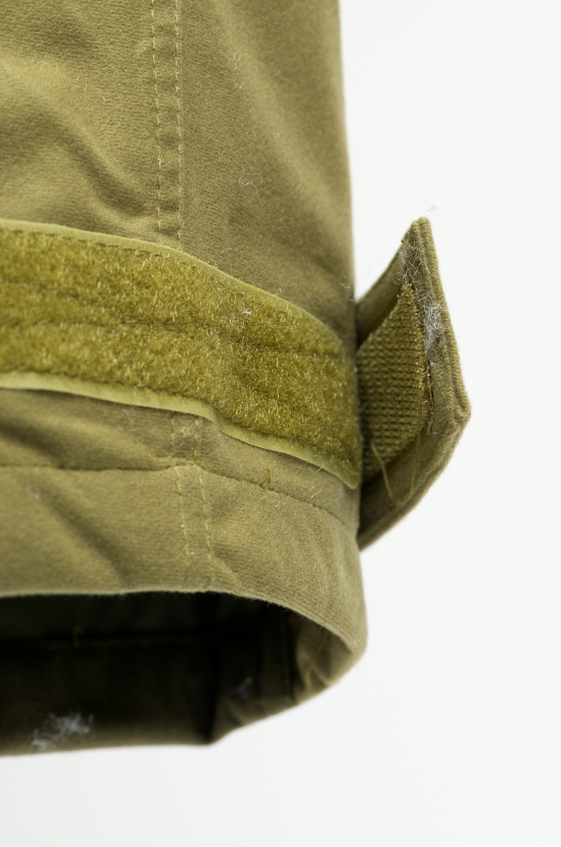 Doverefjell Jeger'n bukse til herre i størrelse medium. Buksa har et ytterfor i børtstet mikrofiber. Den har vanntett membran med tapede sømmer. Jaktbuksa har et isolerende nettingfor som motvirker kondens. Videre har den formsydde knær og sete for best mulig passform og bevegelses frihet. Forhøyet ryggstykke i kors ryggen med elastikk, knapper for bukse seler, solide beltehemper, frontlukking med kraftig borre lås og glidelås. Ekstra utlufting, romslig lår lomme, to dype stikklommer og baklomme, alle med glide lås. Kraftige innstrammings muligheter nede. [Beskrivelsen av buksa er hentet fra omtale på Friluftsmagasinets hjemmeside]