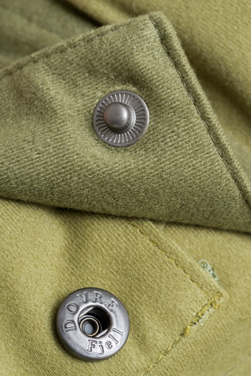 Doverefjell Jeger'n bukse til herre i størrelse medium. Buksa har et ytterfor i børtstet mikrofiber. Den har vanntett membran med tapede sømmer. Jaktbuksa har et isolerende nettingfor som motvirker kondens. Videre har den formsydde knær og sete for best mulig passform og bevegelses frihet. Forhøyet ryggstykke i kors ryggen med elastikk, knapper for bukse seler, solide beltehemper, frontlukking med kraftig borre lås og glidelås. Ekstra utlufting, romslig lår lomme, to dype stikklommer og baklomme, alle med glide lås. Kraftige innstrammings muligheter nede. [Beskrivelsen av buksa er hentet fra omtale på Friluftsmagasinets hjemmeside]