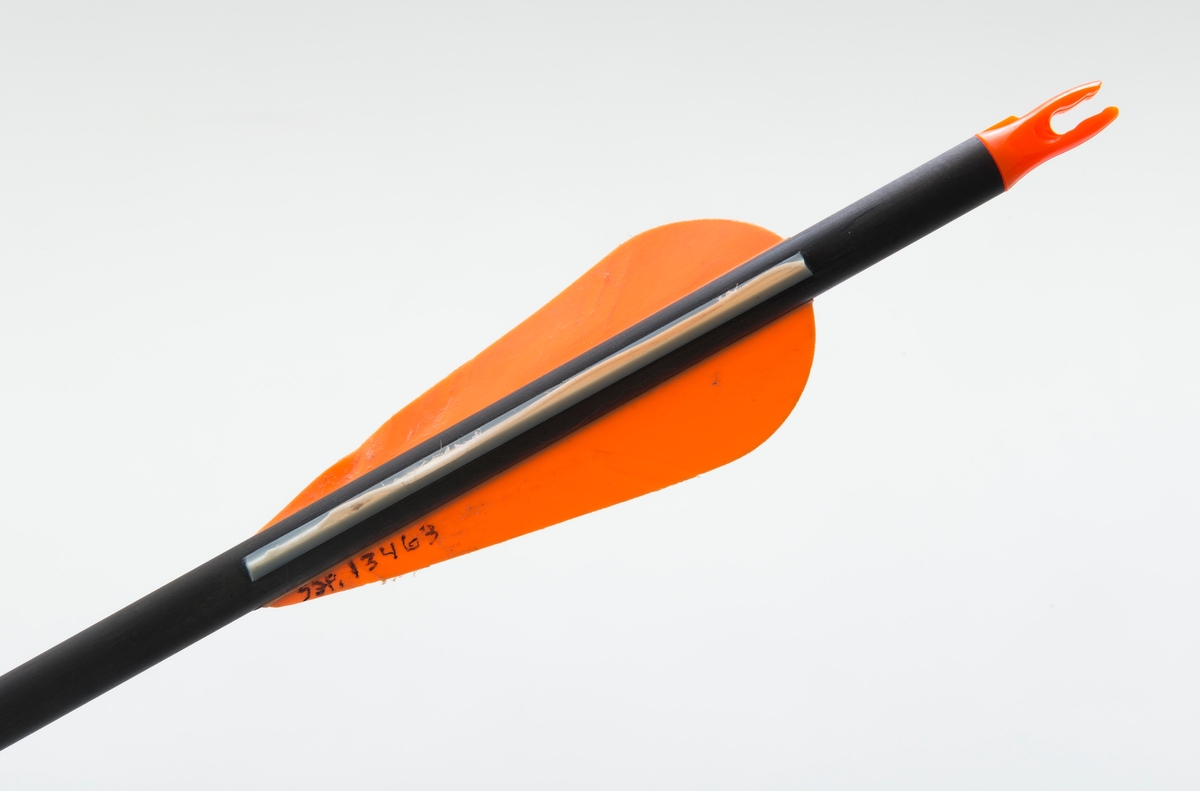 Pil av karbonmateriale (karbonfiber) utstyrt med feltspiss. Pilen har styrefjær av kunststoff i oransje og hvitt. Pilen har en oransje nock av plastmateriale i enden som tres på buestrengen. 
Pilen og har gjenger i ene enden, slik at spissen kan byttes etter behov. 