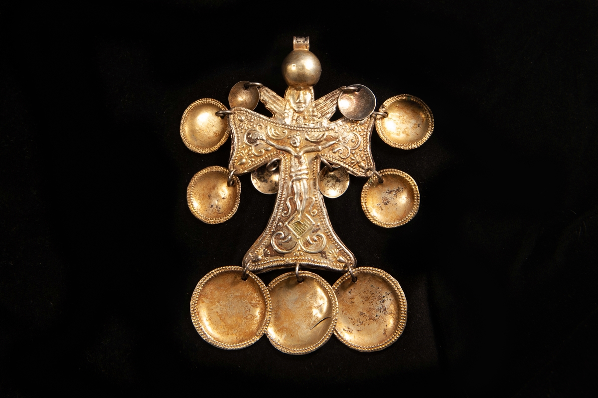 Ett striglakors i ciselerat och förgyllt silver. Motiv i form av Jesus på korset med ett naivt änglahuvud ovanför. Behängt med 11 runda, små plattor ("skålar") av ciselerat och förgyllt silver. Delvis otydliga stämplar.