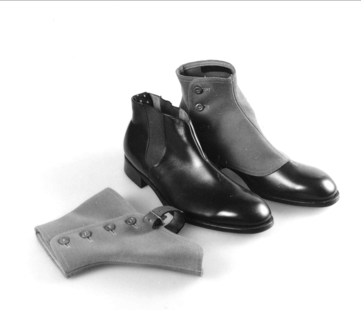 Herrsko, svart skinn av typen "boots" med lågt skaft med sydda sidoresårer. Lädersula och gummiklack. Tillverkare Hästen, Uppsala. Storlek 6½ A, klacken av märket Elg, H-17.Tillhörande damasker av grått kläde, av märket Percival SDE, storlek 42. Knäpps med fyra knappar och skinnrem, med metallspänne, under foten.