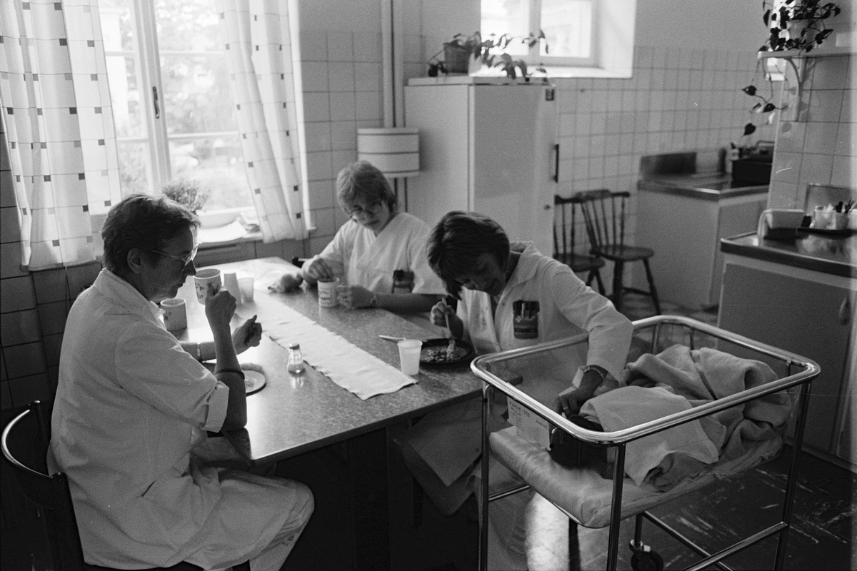 Barnsköterskorna Lisbeth Kastenholm och Ulla-Britt Andersson samt städerskan Britt-Marie Gustafsson passar barn under lunchen, köket, lättvårdsavdelningen Ringblomman, Gillbergska barnhemmet, Sysslomansgatan 37 - 39, Uppsala 1986