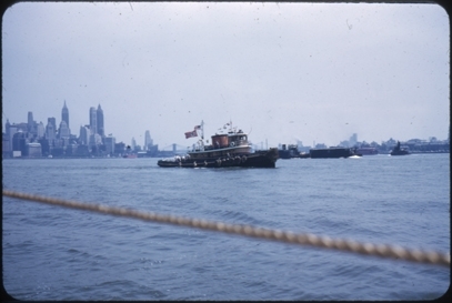 Slepebåt med norsk og amerikansk flagg. Skoleskipsgutter ombord. I bakgrunnen sees Manhattan skyline og Brooklyn. Bildet er tatt fra et annet skip.