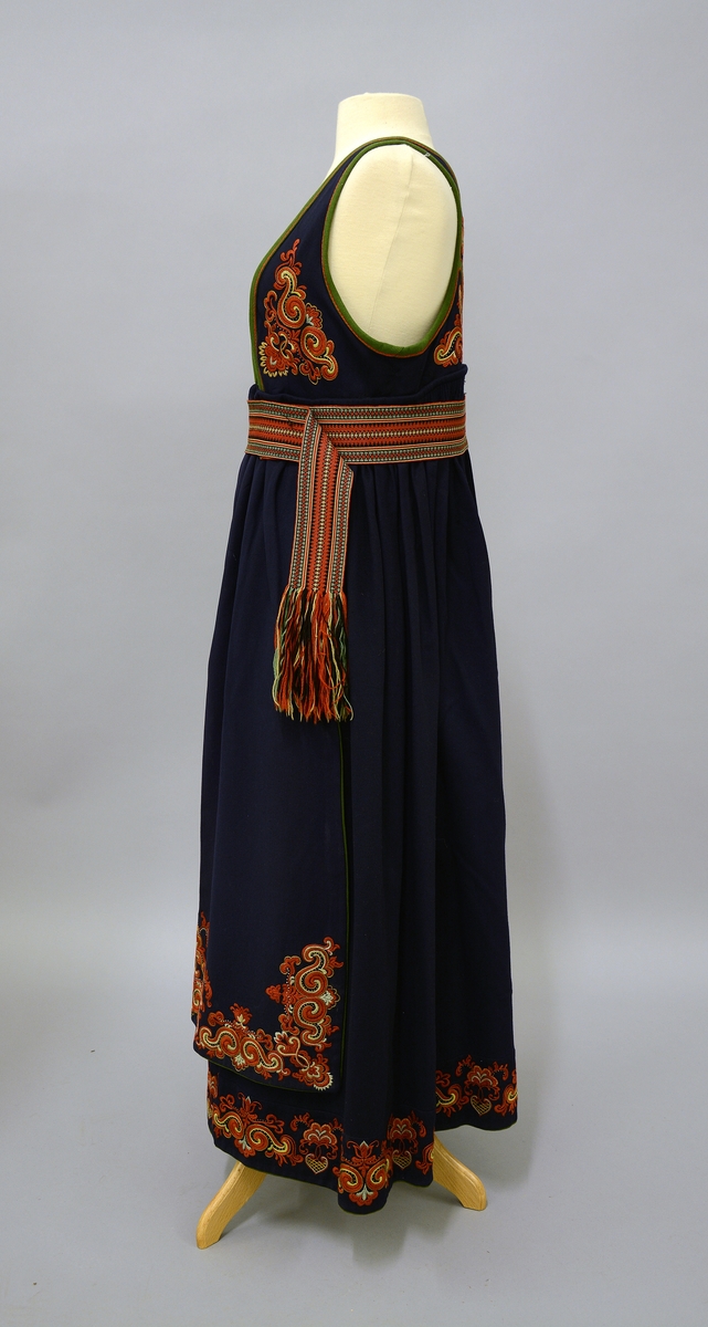 Øst-Telemarksbunad, sydd av Anne Bamle i 1926.TGM-BM.1977:381.A-E
C. Belte. Brikkevevd belte, festet med tråklesting til stakken 1 cm nedenfor baugen. Bredde: 6,5 cm, lengde: 132 cm, hvorav 14 cm frynser som dannes av renningen. Vevd med 63 brikker i mykt 4-tråds ullgarn i farvene rustrødt, gult, grønt og sort med den den rustrøde som dominerende i  midtpartiet og grønne striper på sidene. 1 trykkapp og 3 hekter holder beltet sammen på venstre side 12 cm fra midten, enden med frynsene faller fritt ned.