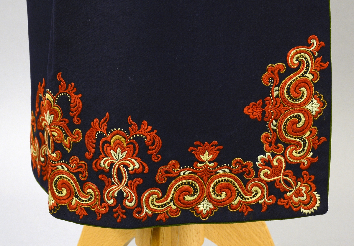 Øst-Telemarksbunad, sydd av Anne Bamle i 1926.TGM-BM.1977:381.A-E 
D. Forkle. Bredde 66 cm nede, opp er det rynket sammen til 34 cm og sydd til en 34 cm lang og 1 cm bred linning, som er tråklet først i stakken. 4 cm nedenfor baugen, slik at brikkebåndet dekker over det. Forkleet er på 3 sider kantet med grønt som stakken nede. Broderiene er dekket av atlas fòr på vrangen. Rosesaum 20cm høy på sidene. 16 cm høy på midten, bygget på samme motiv som stakken. Fra Protokoll.