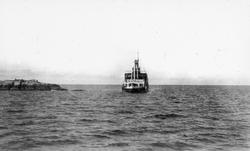 Fartøy på åpent hav, svaberg eller holme til venstre i motiv