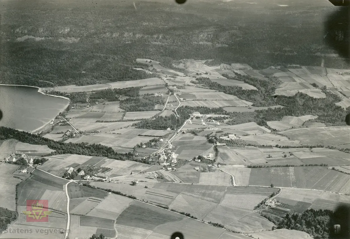 Flyfoto tatt av "Hærens flyvesen og luftforsvar" i 1928. Bildet er i brev fra Vaabeninspektøren for Hærens flyvesen og luftforsvar, datert 12.10.1928, klassifisert som hemmelig bla. fordi jernbane, tettsteder og veganlegg vises. På baksiden av bilder er skrevet følgende: "Nr 33 Fot. av kapt. Lunde, Avd: S.F.A. Dato 1-8-1928 kl: 13:55. Enkelt skråbil. Bar mark. App: Zeiss Br vidde: 25 Form: 13x18. Høide: 700 m. Stedets navn: Svangstranden jbst (?) mot øst Rutenr: 7611. Kart: Oslo rekt." Omslagsark stemplet J.no 3666 1928 G.E.0523-1928.