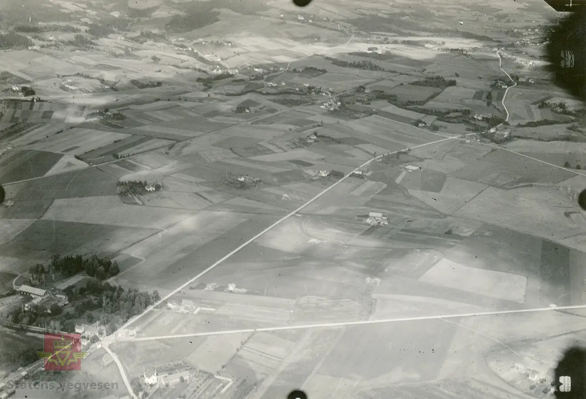 Flyfoto tatt av "Hærens flyvesen og luftforsvar" i 1928. Bildet er i brev fra Vaabeninspektøren for Hærens flyvesen og luftforsvar, datert 12.10.1928, klassifisert som hemmelig bla. fordi jernbane, tettsteder og veganlegg vises. På baksiden av bilder er skrevet følgende: "Nr 17 Fot. av kapt. Lunde, Avd: S.F.A. Dato 30-7-1928 kl: 10:13. Enkelt skråbil. Bar mark. App: Zeiss Br vidde: 25 Form: 13x18. Høide: 700 m Delvis overskyet. Stedets navn: Amtmandsvingen Gilhus mot Lier st. Rutenr: 7495. Kart: Oslo rekt. 1:100000". Omslagsark stemplet J.no 3666 1928 G.E.0523-1928