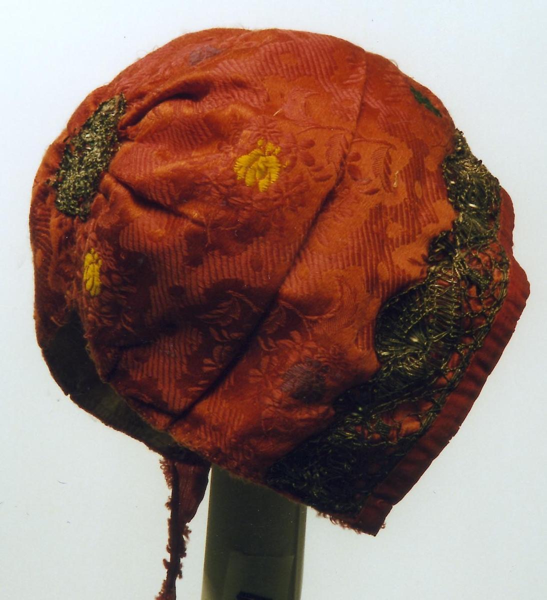 Rød dåpslue med sølvbånd.