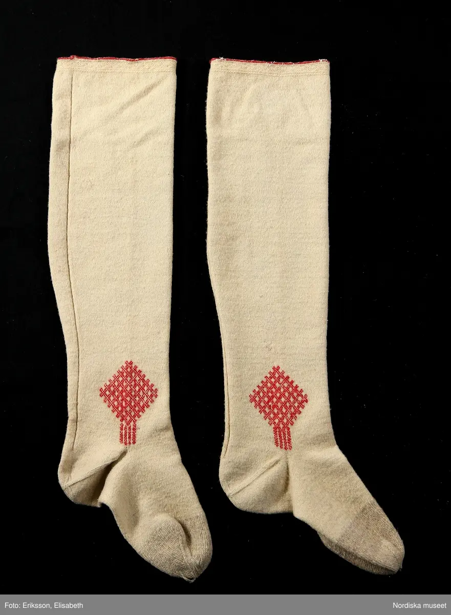 Mansdräkt i flera delar a-d.

a. Rock av svart vadmal
b. Röd väst
c:1-2 Vita strumpor
d. Knäbyxor av sämskskinn
Katalogkort finns.

a. Långrock av svart vadmal. Framstyckena/sidstyckena helskurna, ryggstycket smalt och kort,  avkuret i midjan, rikt veckat bakskört försett upptill med två ulltofsar och med pikerade klaffar en vid var  sida om skörtet. Svängda ärmar med 2 sömmar och blindslag med sprund oknäppt med 2 hakar och hyskor. Ståndkrage. Skoning av hemvävda ylleband i flera färger längs livets insidor, knäppning med hakar och hyskor.
"Dylika rockar tillhörde högtidsdräkten, vid mindre fester och till kyrkan brukades grå rockar af liknande snitt, ett snitt som gaf anledning till benämningen ´fiolen´för nysockenströjans ryggtafla ".
b. Väst av röd vadmal med ryggstycke av grovt oblekt linne i spetskypert. Hög ståndkrage och utvikta slag, med en uddklippt vadmalsremsa i kanten, dubbelknäppning med  vitmetallknappar, fästa på insidan med skinnremsa, knapphål tränsade med grönt ullgarn. 2 sidfickor med list. Foder av oblekt linnelärft, på kragens insida en bit av ryggtyget mitt bak.
c:1-2 . Strumpor slätstickade i tvåändstickning av fint vitt 1-trådigt ullgarn. Uppläggningsvarvet med rött och vitt ullgarn,  smal mönsterstickad överkant. Häl och tå av annat naturgrått garn. Mitt bak en sömmarkering med en avig maska. Vid anklarna broderade rombiska figurer i genombrutet mönster, kallas "löver" i rött ullgarn.
d. Knäbyxor av gult sämskskinn, med bred lucka med 5 knapphål, midjegjord knäppt med 2 knappar. Knapparna är av flera olika sorter av mässing, en av hängselknapparna av horn, 2 bak saknas. Midjegjorden fodrad med linnelärft. Knäsprund knäpps med 4 hakar och hyskor. Flikar vid sprunden uddklippta.
/Berit Eldvik 2010-01-08
