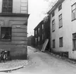 I slutet av 1950-talet önskade man bredda Västgötegatans nedre del där byggnader inom kvarteret Vårdtorent skapade en flaskhals. Bilden visar Norra Bryggaregatan, nuvarande Mäster Påvels gränd, sedd från korsningen med Västgötagatan, där huset närmast till höger kommer att rivas för att nå den önskade breddningen. Vy mot norr.