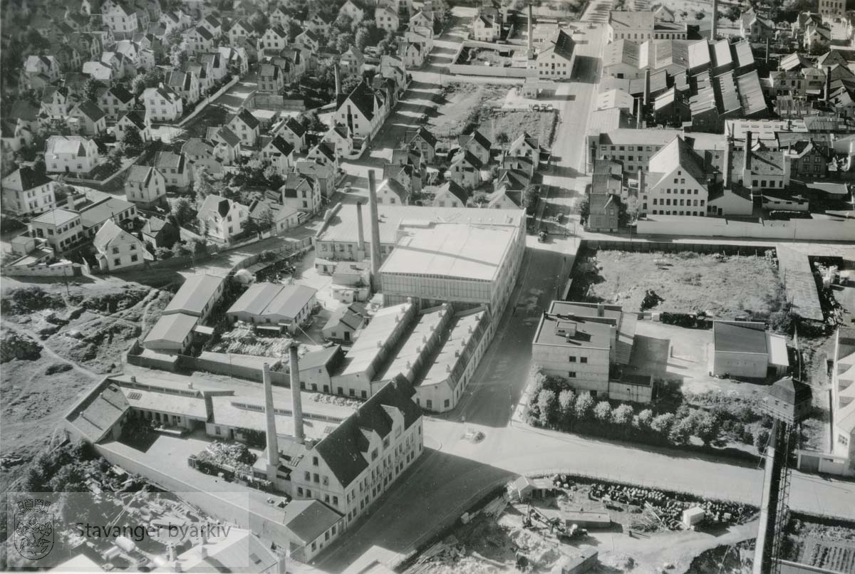 Mot nordvest...Til venstre: Preserving Co. Nor og Vestlandske Gummivarefabrikk. .I høyre bildehjørne nederst: Stavanger Tinnfabrikk med hagltårnet / haggeltårnet..Høyre hjørne øverst: Stavanger Blikktrykkeri...Gateløpene er fra venstre: Erfjordgata, Johannesgata og Haugesundsgata. Kryssende gater er Rennesøygata, Kvitsøygata og Avaldsnesgata.