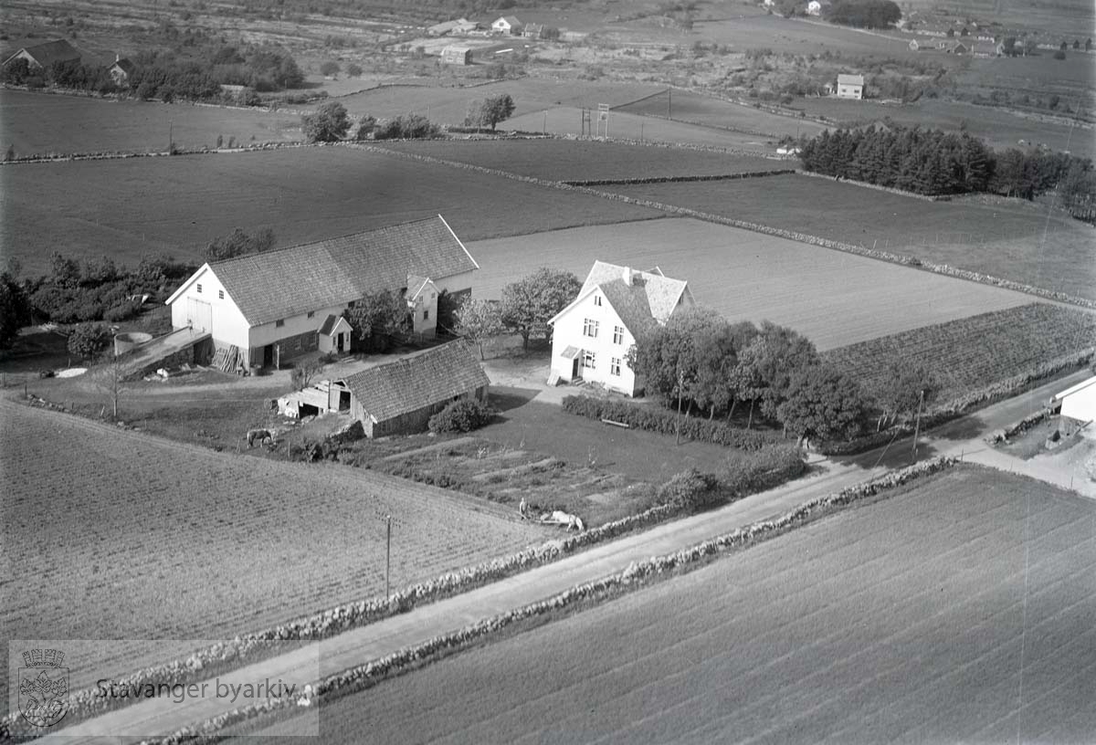 Stavanger Madla bydel. Veien til Madlasandnes går t.v. i bildet. Mot N.Ø..Gården her tilhørerHenrik Molaug. .Veien går til Madlasandnes. Madlaleiren (Noreleiren) øverst i høyre hjørne.Her ligger også gården til Andreas Thorsen. Øverst t.v. er gården til Torkelsen som har grense mot Regimentveien. Mellom gården og Middelalderkirken (her skimtes en av de gamle inngangene til kirkengården) ligger hele Hafrsfjord-skolekomplekset. ..