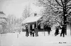 VUXNA OCH BARN I SNÖN FRAMFÖR ETT BOSTADSHUS