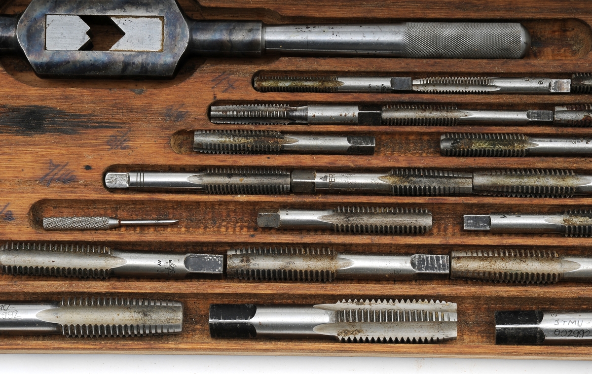 Gjengevertøy i original trekasse fra produsenten Greenfield tap and Die Corporation, USA bestående av seks (runde) gjengebakker/-snitt, 19 gjengetapper, ett svingjern for gjengetapper og ett svingjern for gjengebakker. Tappene øverst i eget brett. Skrinet og verktøyet bærer preg av å ha blitt brukt, men er i god stand.