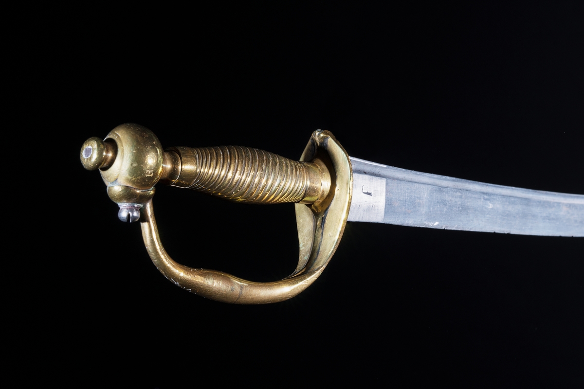 Infanterihuggare, obekant härkomst, förändringsmodell/1748-95 för Svea artilleri. Material: Klingan av stål, något böjd, fästet av mässing. Ingen stämpling eller märkning. Troligen hemförd som krigsbyte. Tillhör statens trofésamlingar.