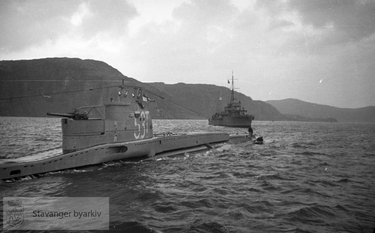 I dårlig vær på norskekysten ble dybderorene akter på den nye britiske u-båten HMS "Triad" skadet. Destroyerne HMS "Inglefield" - D02 - og HMS "Maori" - F24 - gikk til assistanse og eskorterte "Triad" inn i Mastrafjorden 30.11.1939.. .Offiserer på den norske torpedobåten "Stegg" bordet "Inglefield" for konferanse. "Triad" ble først forsøkt reparert i Mastrafjorden, men da dette ikke lyktes måtte u-båten taues til Rosenberg mek. verksted for reparasjon. De to destroyerne forlot da norsk farvann.. .Alle de fire ovenfor nenvte skipene i foto-serien gikk tapt i løpet av krigen...Heist kommando:."Stegg" 1921-1940."Triad" 1939 -1940."Inglefield" 1937 - 1944."Maori" 1938 - 1942..(Opplysninger gitt av Einar Haualand, 30.10.2022)...