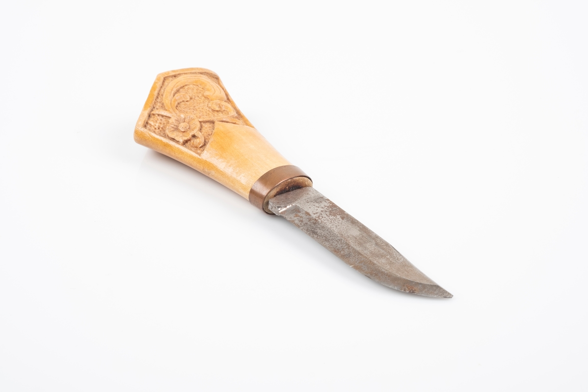 Tollekniv med skaft i tre og knivblad i jern. Det er utskåret akantusmønster på skaftet. Bolsteret er i kobber.