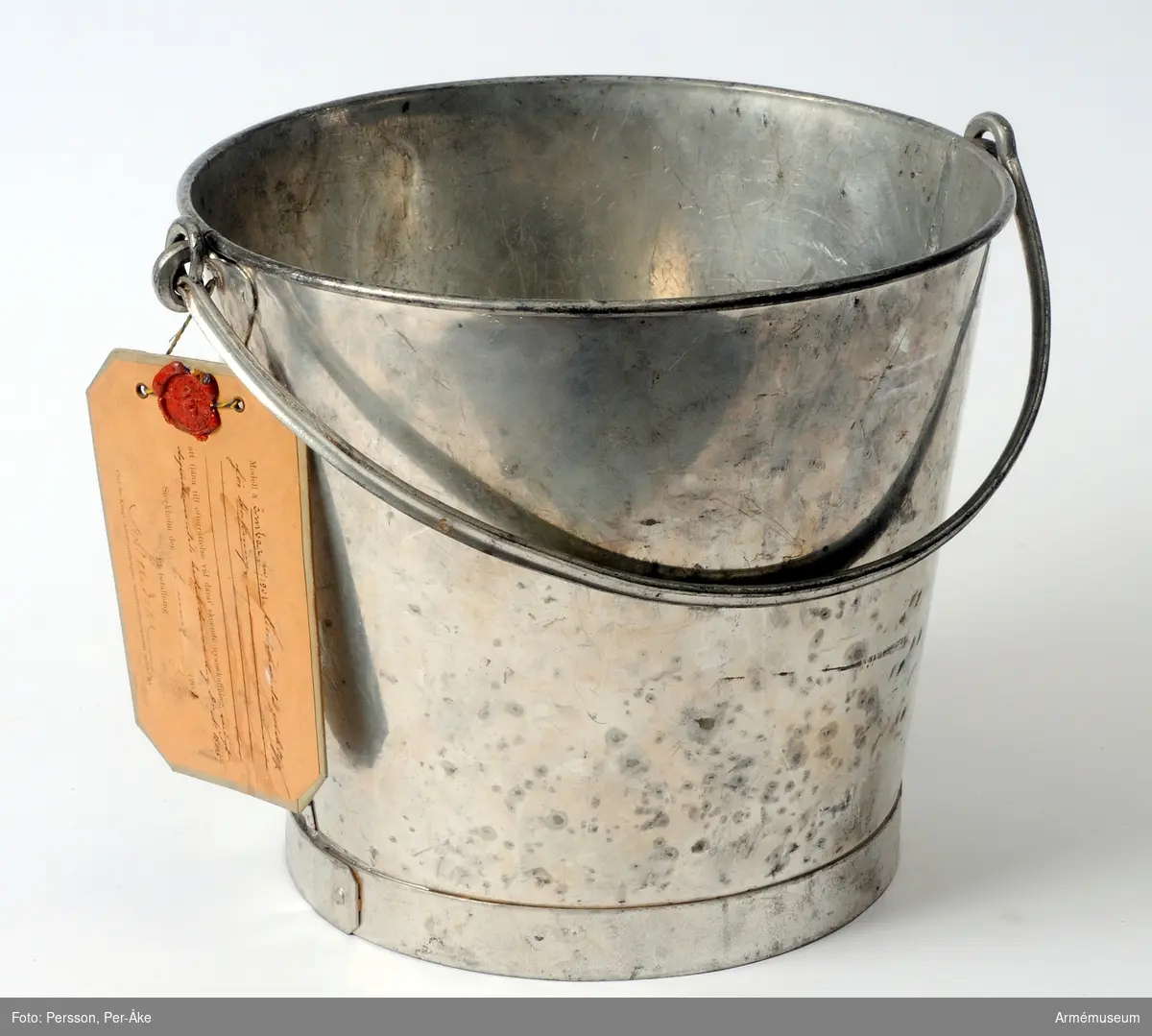 Text på vidhängande modelllapp:
"Modell å ämbar m/1901 tillhörande verktyg för bakning att tjäna till efterrättelse vid deraf skeende nyanskaffning enligt departementets beslut denna dag Dii No 1505. Stockholm den 1 mars 1901"