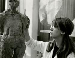 En elev vid Konstfackskolan modellerar en skulptur i lera.