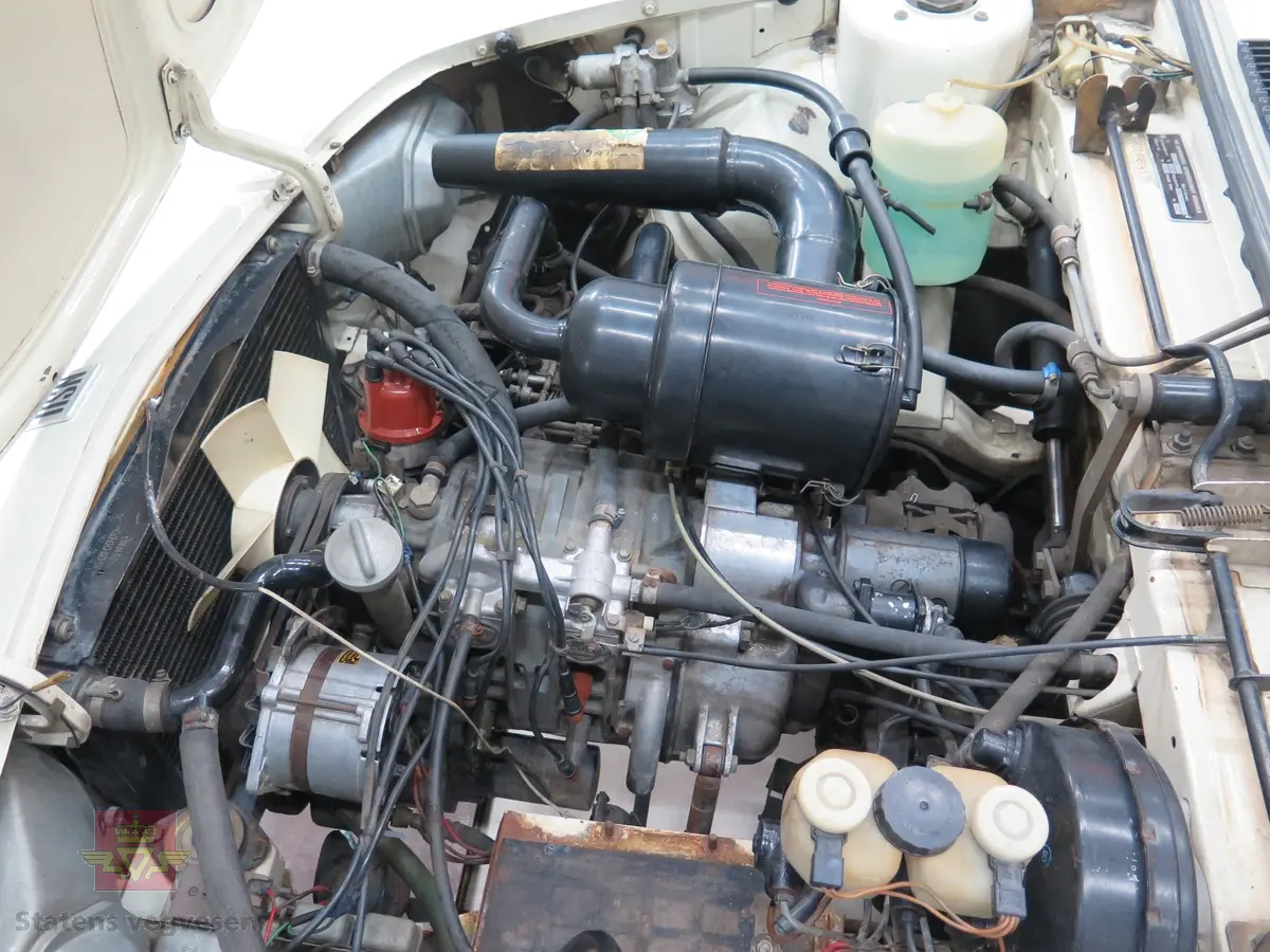 NSU RO 80. 4-dørs hvit bil med brunt interiør. Bilen har en bensindrevet dobbel NSU/Wankel rotasjonsstempelmotor, med sylindervolum på 994 kubikkcentimeter (cm3), og effekt på 115 DIN HK. Dekkdimensjon foran og bak skal standard være 175 HR 14. Framhjulstrekk. Girkasse med 3 gir framover pluss revers. Kilometerstand er 75385.