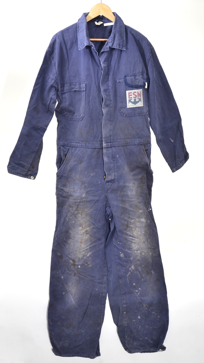 Blå bomullskjeledress i størrelse 56 med logo på venstre brystlomme. Lukking med metallknapper. To brystlommer og to stikklommer i front og to baklommer og strikk i ryggen.  
Logoen er utformet som et kvadrat med hvit bunnfarge og bokstavene ESN i rødt øverst og et stilisert blått anker under.
Kjeledressen har et metallmerke i venstre brystlomme - nr. 165; brukers arbeidsnummer - som var viktig i forbindelse med vask av arbeidstøyet.