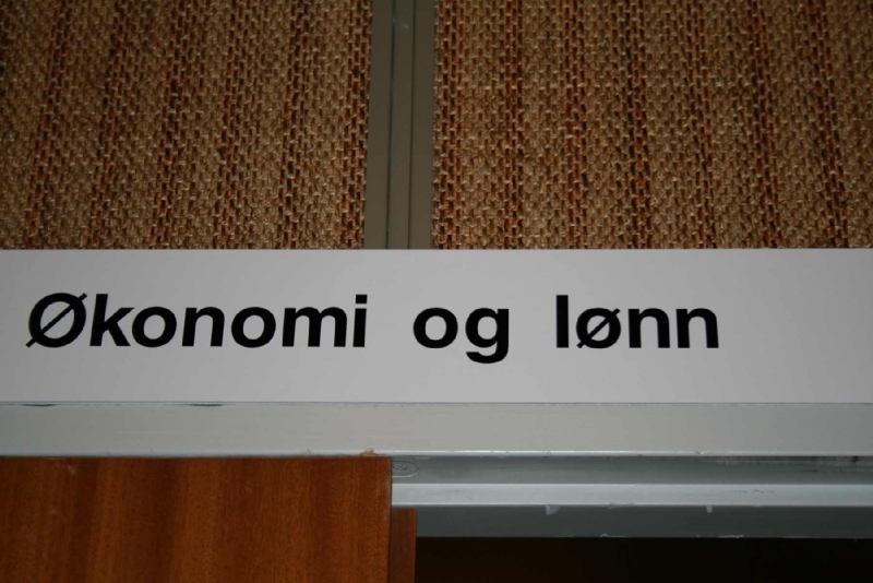 Leirfjord, Leland. Skiltet over døra inn til økonomi og lønn  på kommunehuset. Fotografert fra resepsjonen.