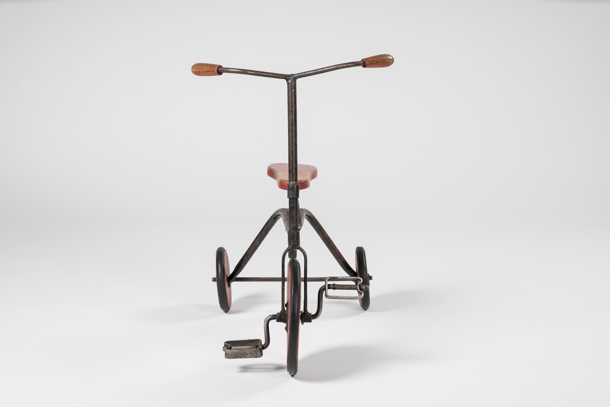 Form: Ramme av hulrør, forhjul med pedaler, flatt, innsvinget sete.
