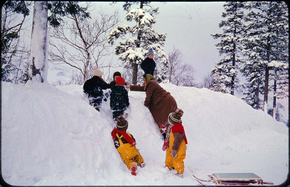 Kippermoen barnepark, 1961-62. Barn som leker i snøen. Barnehagetante ordner opp.