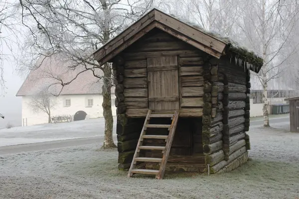 Bildet viser kjona ute om vinteren. Det er rim på bakken og det er kaldt. Kjona er et høyt hus som er laftet.