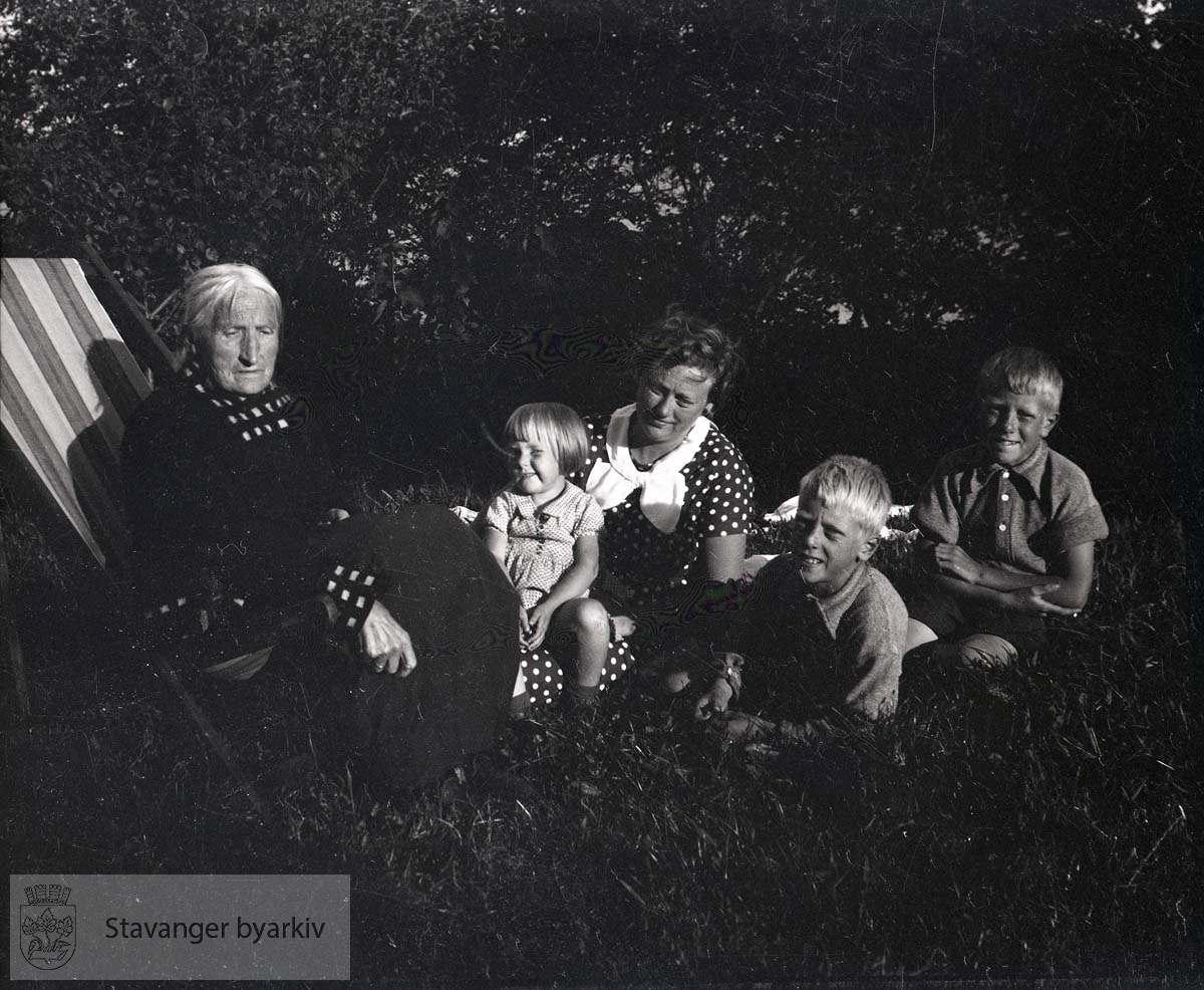 Eldre kvinne i fluktstol, Ellinor og de tre eldste barna Jan Christian, Per og Bjørg i hagen.