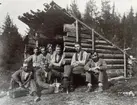 Linjelag som byggde telefinlinjen från Enskogen Till Tevansjö 1924. Man vilade middag vid denna flottkoja, som var byggd i form av ett gapskjul. Männen i främre raden från vänster Anders Berglöf, Helmer Hallenius, Olle Blomgren och Johan Thorell. I kojöppningen Olle Djäkner, Manne Haglund, Järvström och Englund. Linjegubbarna boode inhysta i bygdens gårdar, men till helgerna cyklade man hem, en sträcka på omkring 4 mil.