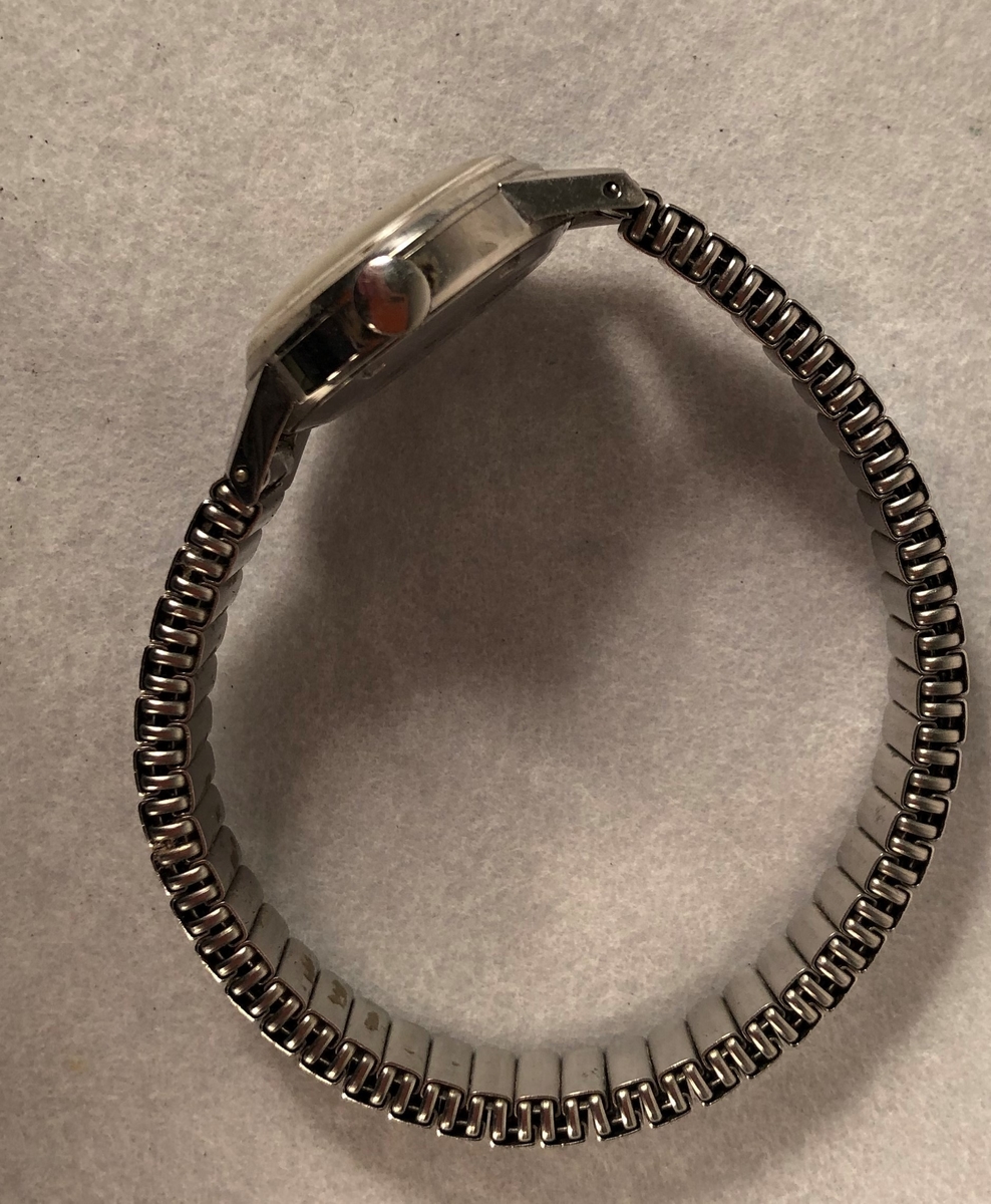 Klokke av stål med lenke med sekundviser (runding). Trekkes.