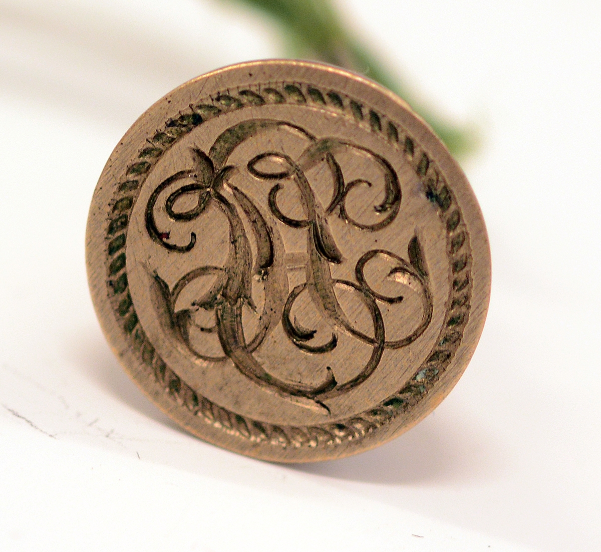 Signet av bronse, med initialene H.I. i dekorativ inngravering og ring rundt, støpt av Skiens gamle kirkeklokker, i klokkeform med feste på toppen og ring i. Medfølgende notat fra giveren til museet.