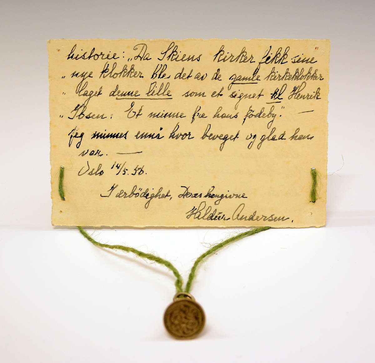 Signet av bronse, med initialene H.I. i dekorativ inngravering og ring rundt, støpt av Skiens gamle kirkeklokker, i klokkeform med feste på toppen og ring i. Medfølgende notat fra giveren til museet.