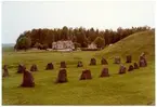 Badelunda sn, Anundshögsområdet, Långby.
Skeppssättning och gravhög med byggnader i bakgrunden.