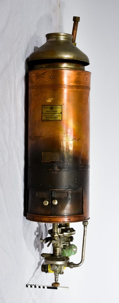 Bronsfärgad varmvattenberedare med texten "Skultuna Varmvattenapparater aktiebolaget Svenska metallverken Skultuna bruk Västerås Skultuna" , WA 35, 52971 på sig.