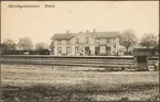 Stationsområde och bangård med personal på perrong.