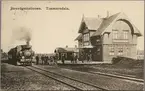 Vy på stationsområde med personal vid ånglok och dressin.