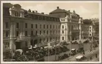 Gatuvy på stationshus och parkering med bilar.