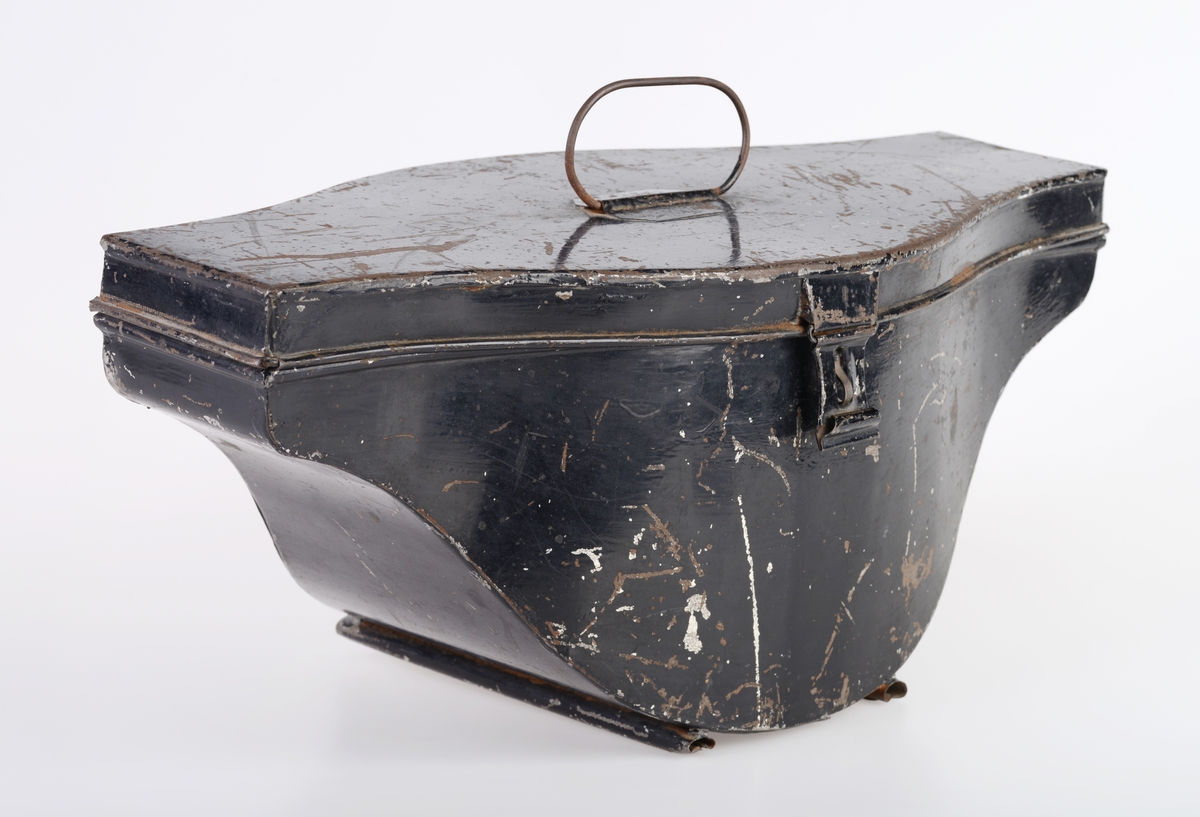 En hatteboks (FTT.56303.01) som inneholder en snutehatt (FTT.56303.02), et bandolær (FTT.56303.03) og en epålett (FTT.56303.04).  
FTT.56303.01:
Hatteboksen er laget av blikk og er svartlakkert utenpå. Lokket er hengslet på baksiden. Oppå lokket er det et enkelt håndtak. I fronetn er det en hempe for hengelås. Den har to lave bein som er laget av sammenrullet blikk. Boksen har form tilpasset hatten. Esken har ikke fôr, men det ligger et papir i bunnen.
FTT.56303.02:
En svart uniformshatt, nærmere bestemt en snutehatt eller en tosnutet hatt. Det er gullbånddekor på hver snute. På den ene siden er det festet en stor kokarde i rødt, hvitt og blått. Over denne er det to flate gullbånd som ender i en spiss. I enden er det en gullfarget metallknapp med et anker med en kongekrone over. Hatten er laget av svart silkefloss med svarte silkebånd langs kanten. Hatten har hvitt silkefôr og svettebånd av brunt lær. På svettebåndet er det festet brune skinnreimer til å feste under haken. På den ene siden er det festet en hvit silkesløyfe. Silkefôret har informasjon om produsent, se "Påført tekst/merker". Det er også bilde av en edderkoppe og et edderkoppnett. Hatten har avstivning ved hjelp av papp. Hatten er håndsydd.
FTT.56303.03:
Et bandolær laget av svart skinn, svart silkestoff og messing. Midjebeltet har en spenne midt foran. Spennen har motiv av et anker med en krone over. På innsiden av beltet er det sydd fast en skinnreim med metallhull til å regulere livvidden. Skulderreimen er festet i midjebeltet med metallringer. Delene til skulderreimen festes sammen med to fjærbelastende kroker. Ved sammenføyningen skulderreim og midjebelte er det påmontert en liten kjetting med krok.
FTT.56303.04:
En skulderklaff til uniform. Oversiden består av svarte- og gullfargede flettede snorer. På undersiden er det sydd på svart ullstoff som er like bred som klaffen. I den ene enden er det sydd på en svart knapp som ullstoffet kan festes i.